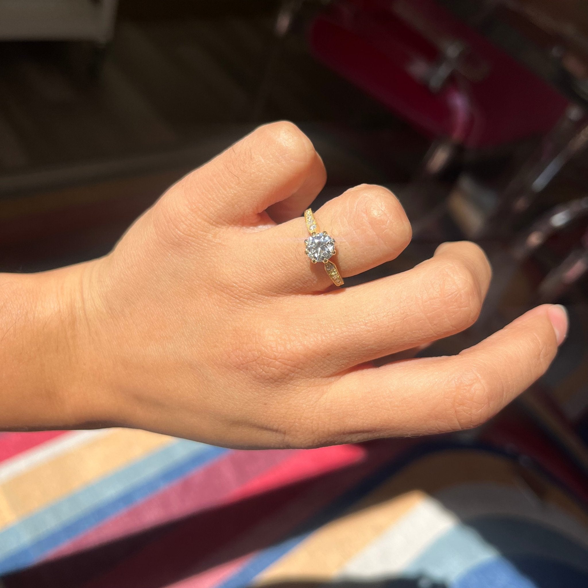 Close-up of antique style diamond ring, elongated OEC center with old cut side stones. Shown on a hand