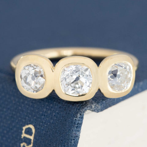 1.53ctw old mine cut diamond bezel set trilogy ring with open gallery, 18K yellow gold