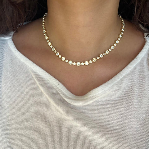 Close-up of vintage-style OEC diamond necklace, alternating bezel-set stones in yellow gold.