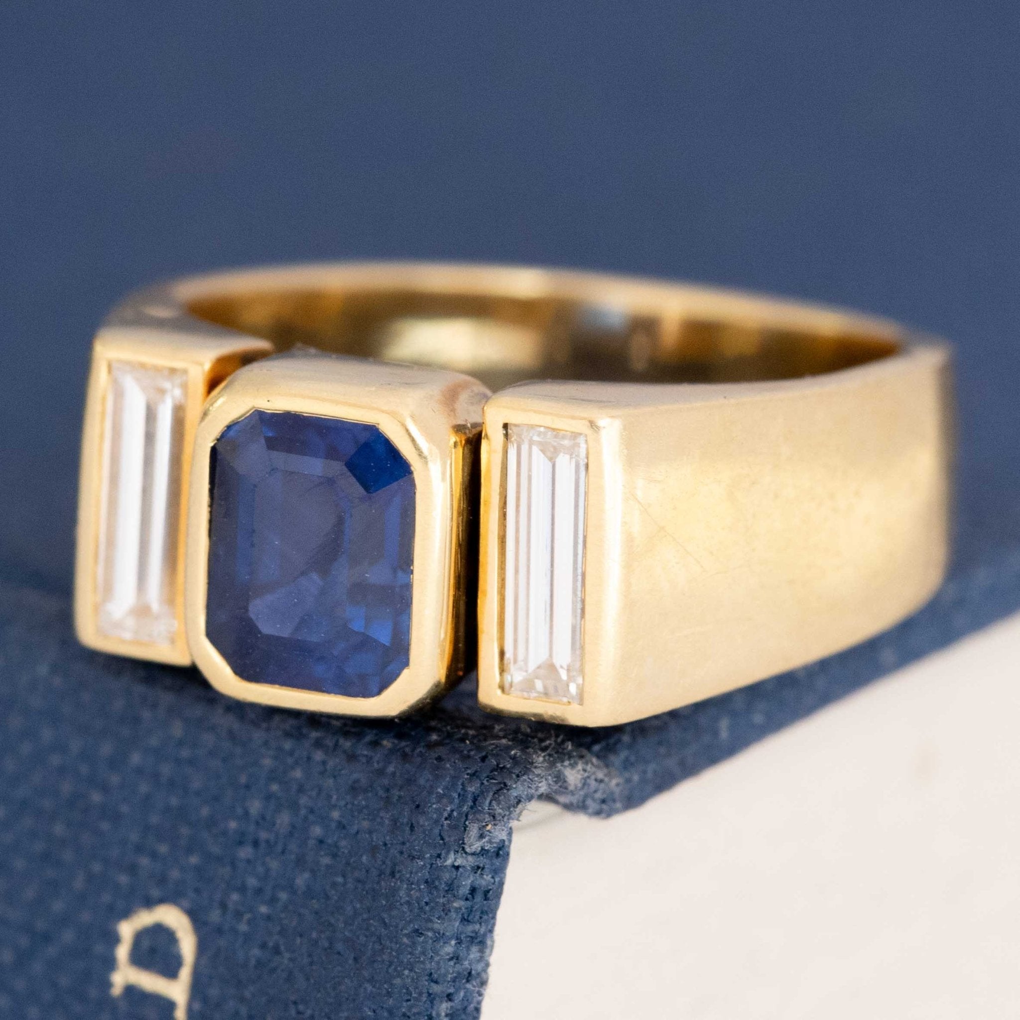 Side angle of sapphire and diamonds mounted in bezel/tension gold frame