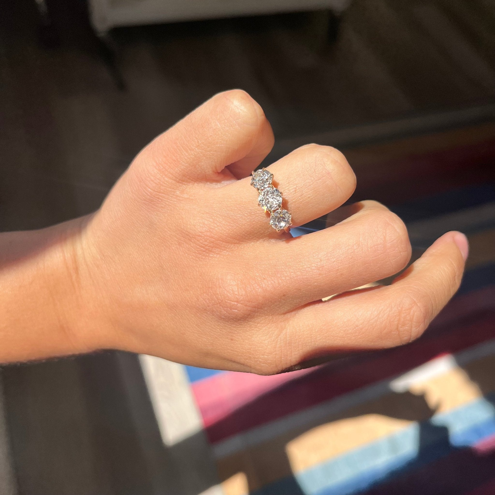 hand shot of an antique 3-stone ring set with chunky old mine cut diamonds in a rosy yellow gold. Perfect vintage engagement ring choice,
