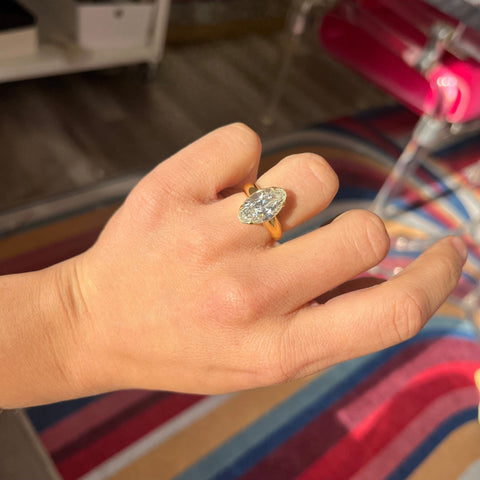 Sculptural yellow gold diamond solitaire in north south orientation shown on ring finger.