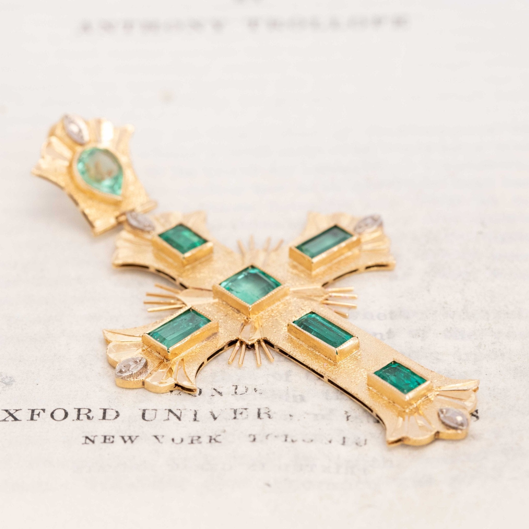 Baroque-style gold cross pendant with emerald gemstones
