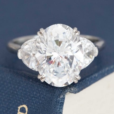 Oval cut diamond engagement ring by Victor Canera in platinum with half moon side stones.