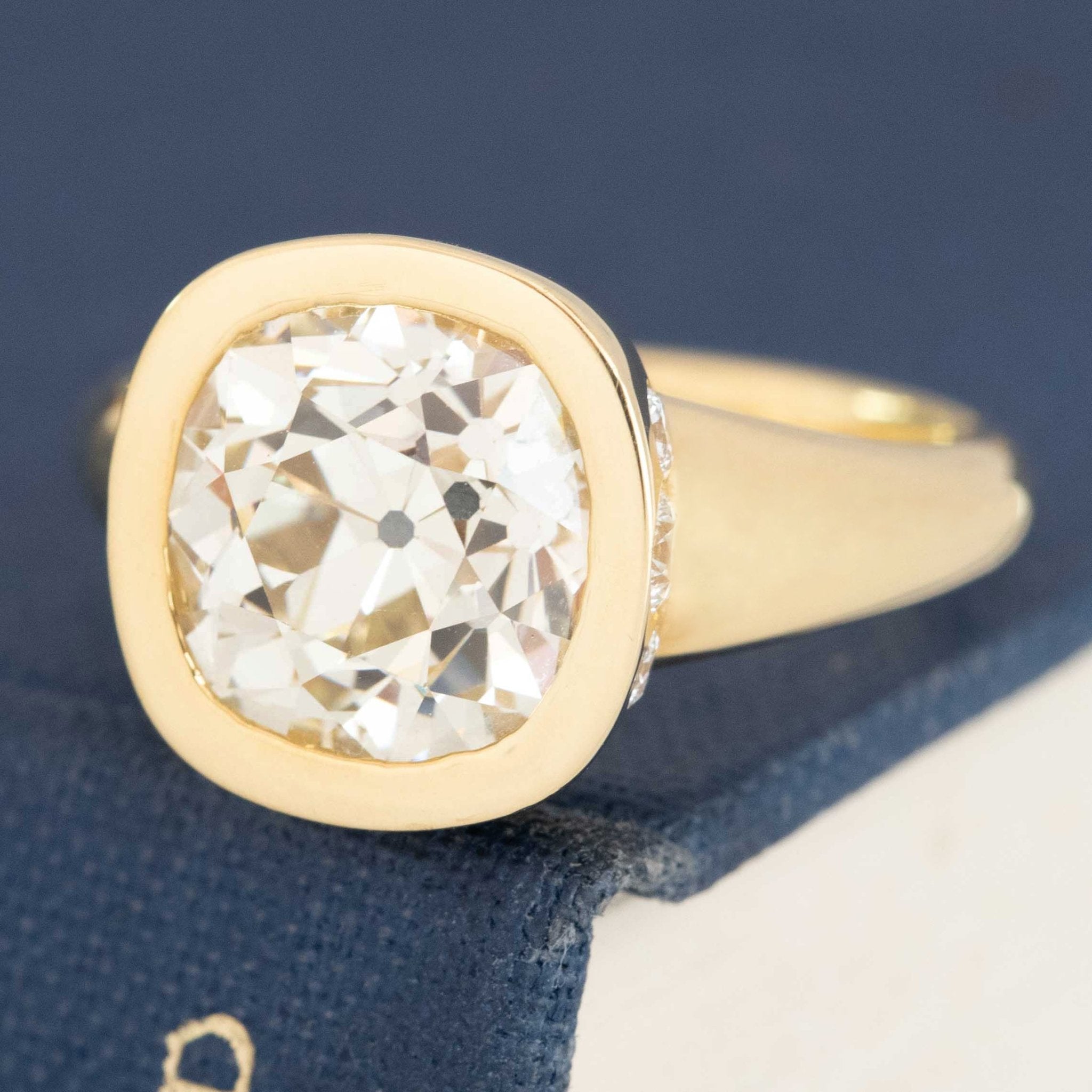 Side profile of bezel solitaire ring, showing polished yellow gold band and bezel edge