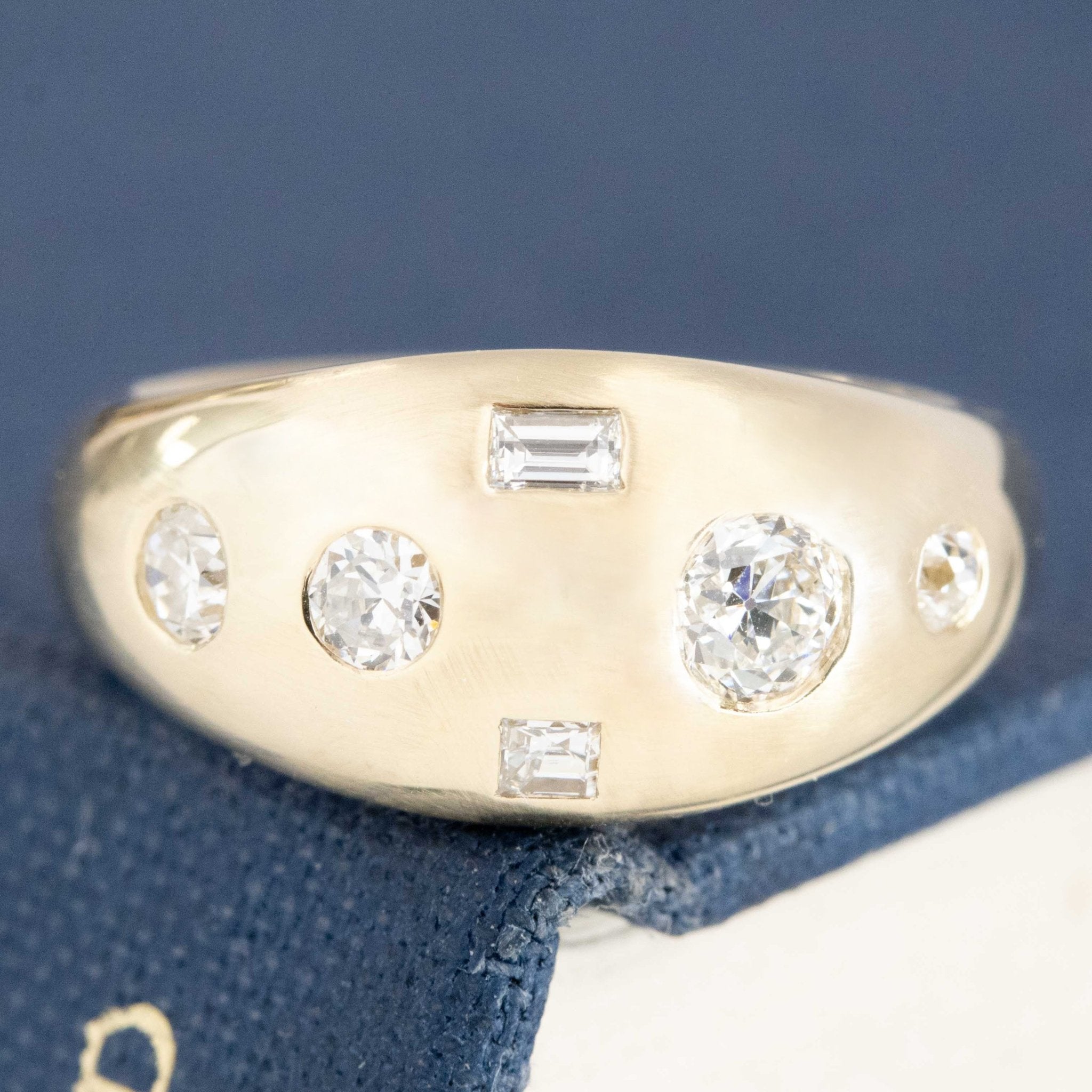A bombe-style yellow gold ring featuring a cluster of round and baguette cut diamonds set in a random, nonsensical pattern.