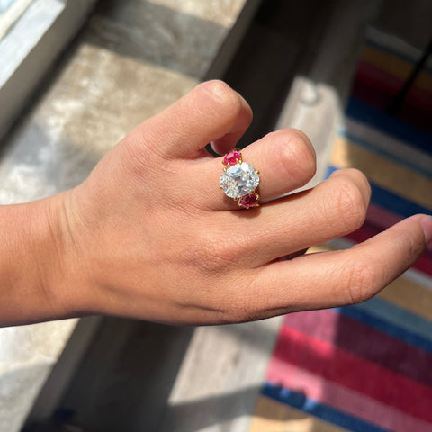 Antique three-stone ring with Old Mine Cut diamond center and vivid spinel sides shown on ring finger
