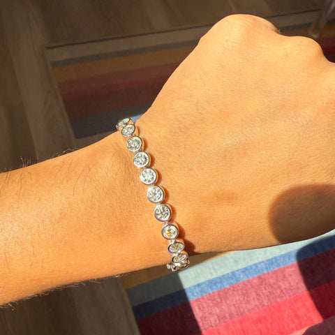 Full view of platinum diamond tennis bracelet on jewelry stand. Vintage-style diamond tennis bracelet sparkling in natural sunlight