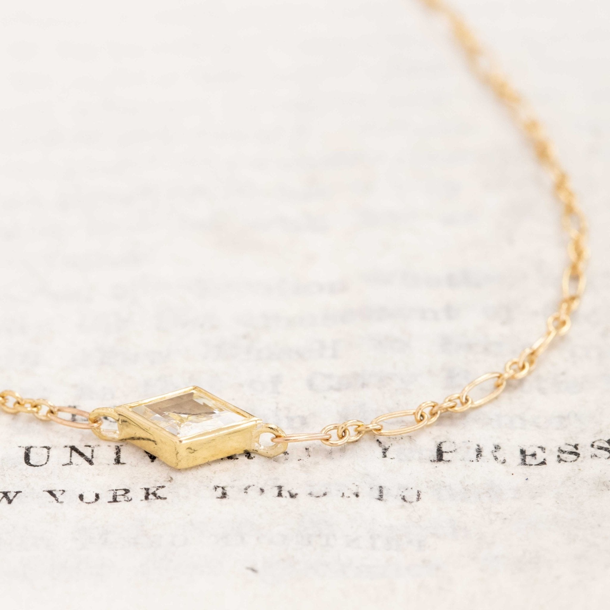 Close-up of vintage-inspired kite diamond pendant in bezel setting, 18k yellow gold and 14k chain.