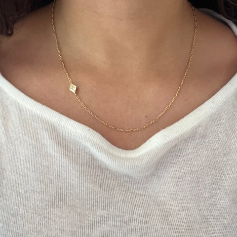 Unique solitaire necklace with .90ct kite diamond placed on the side of a gold chain. Being worn on a neck.