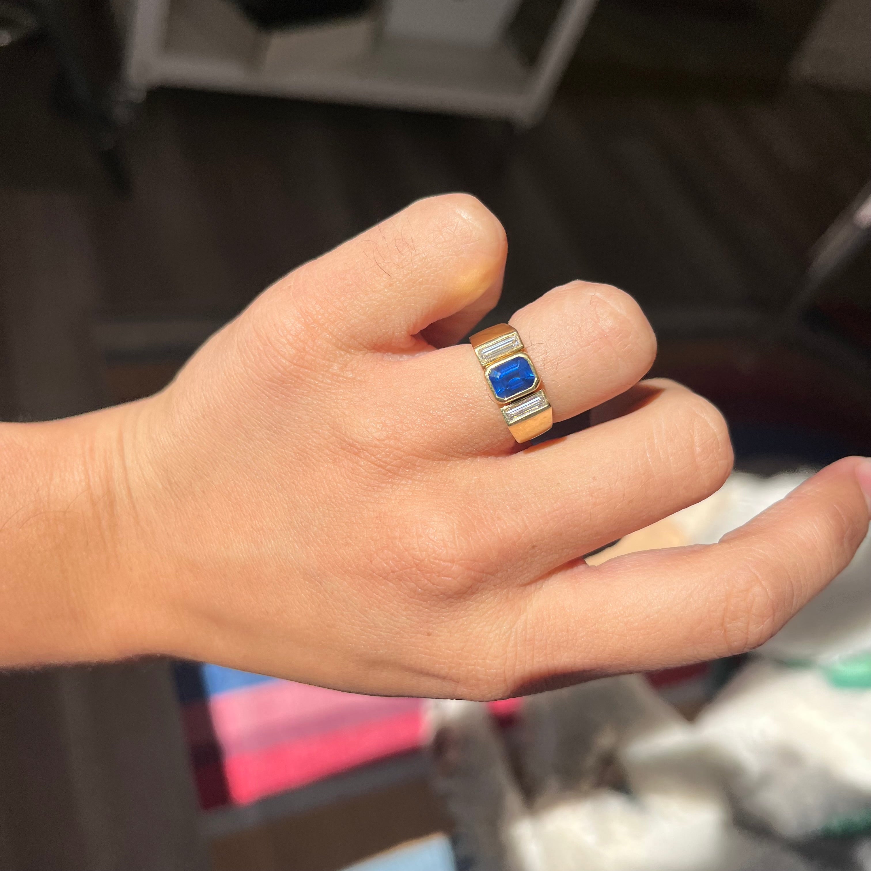 Ring on hand displaying vivid blue sapphire center in geometric gold setting