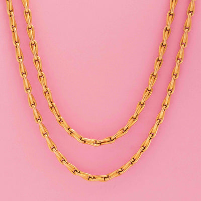 Antique French long chain necklace in 18kt yellow gold, 62 inches in length, on pink background