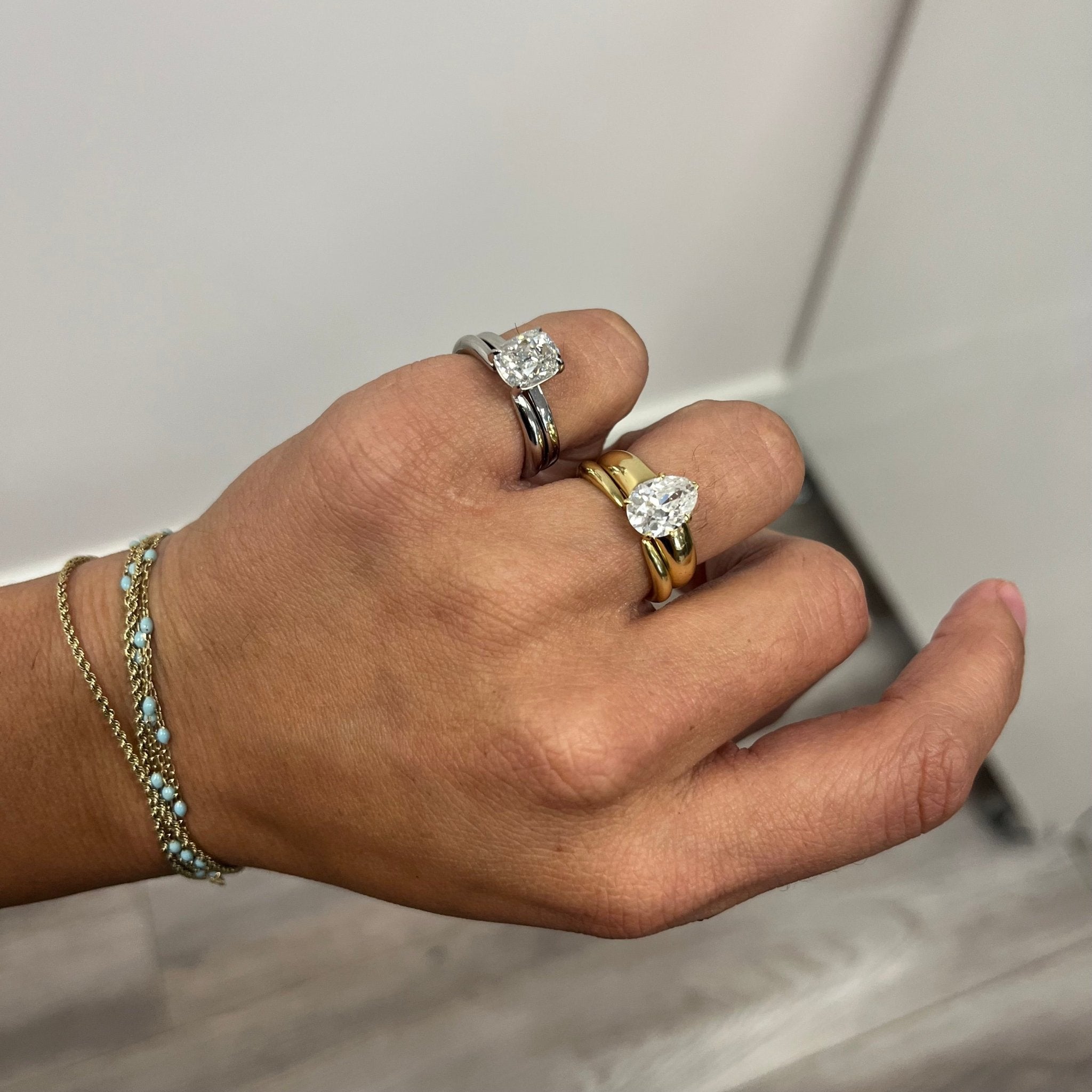 Antique lovers’ "Arc" Wedding Band in Yellow Gold stacked with a diamon solitaire in yellow gold on the ring finger. On the pinky ring resides the same set of rings in platinum.