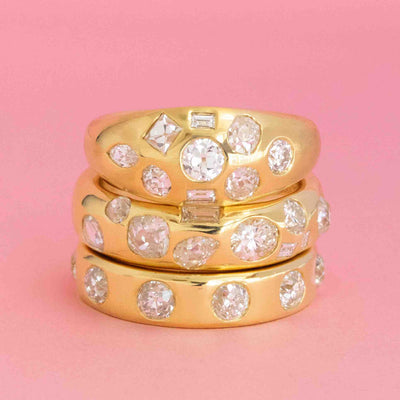 Stacked gold scatter bands with mixed antique-cut diamonds on pink background