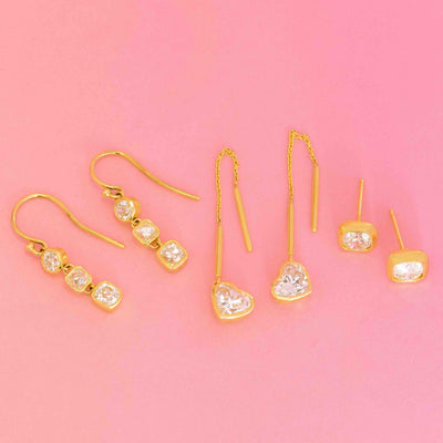 JbyG vintage-inspired gold earrings featuring diamond studs, heart-shaped threaders, and three-stone dangles in bezel settings