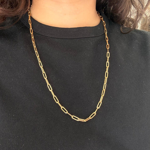 Gold chain necklace on a person wearing a black shirt