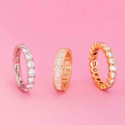 Three antique diamond eternity bands in yellow gold and platinum standing side by side on pink background