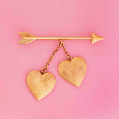 Retro Tiffany & Co. double heart and arrow pin in 14kt yellow gold on pink background