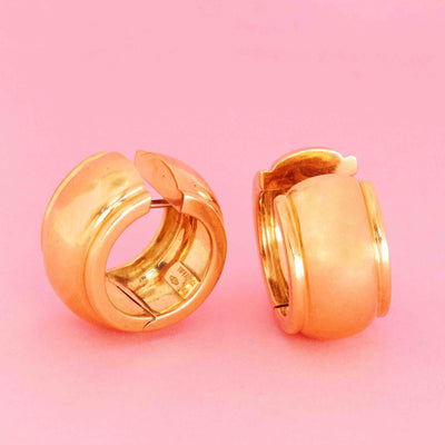 Vintage gold huggie earrings by Tiffany & Co. in 18kt yellow gold on pink background