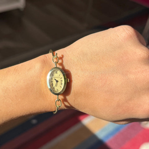 Gold wristwatch on a person's wrist with a blurred background