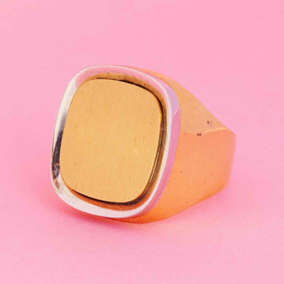 Vintage Cartier cushion signet ring in two-tone 18kt gold with white gold bezel on pink background