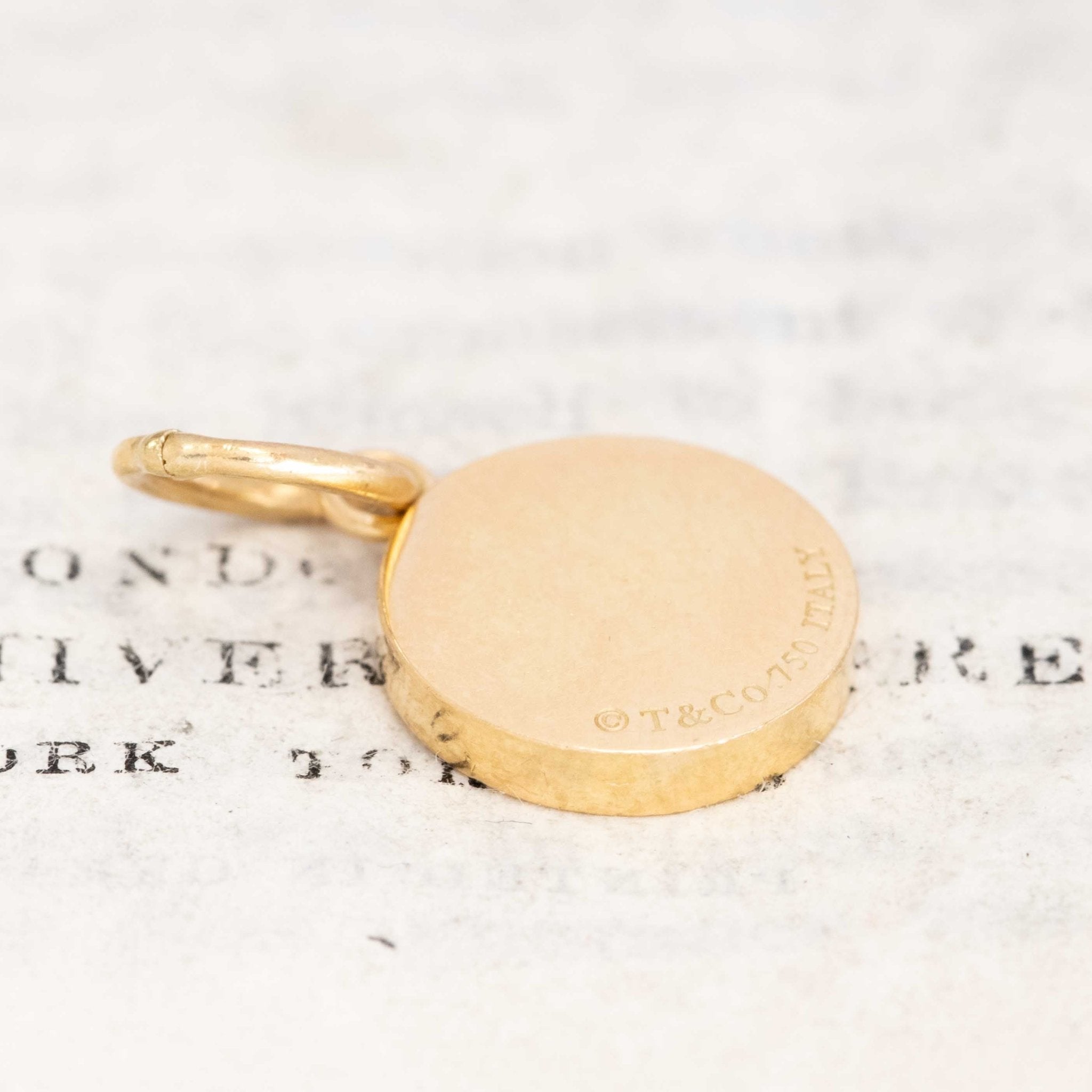 18k gold Tiffany medallion pendant featuring diamond cluster and engraved T & Co 1837 design.