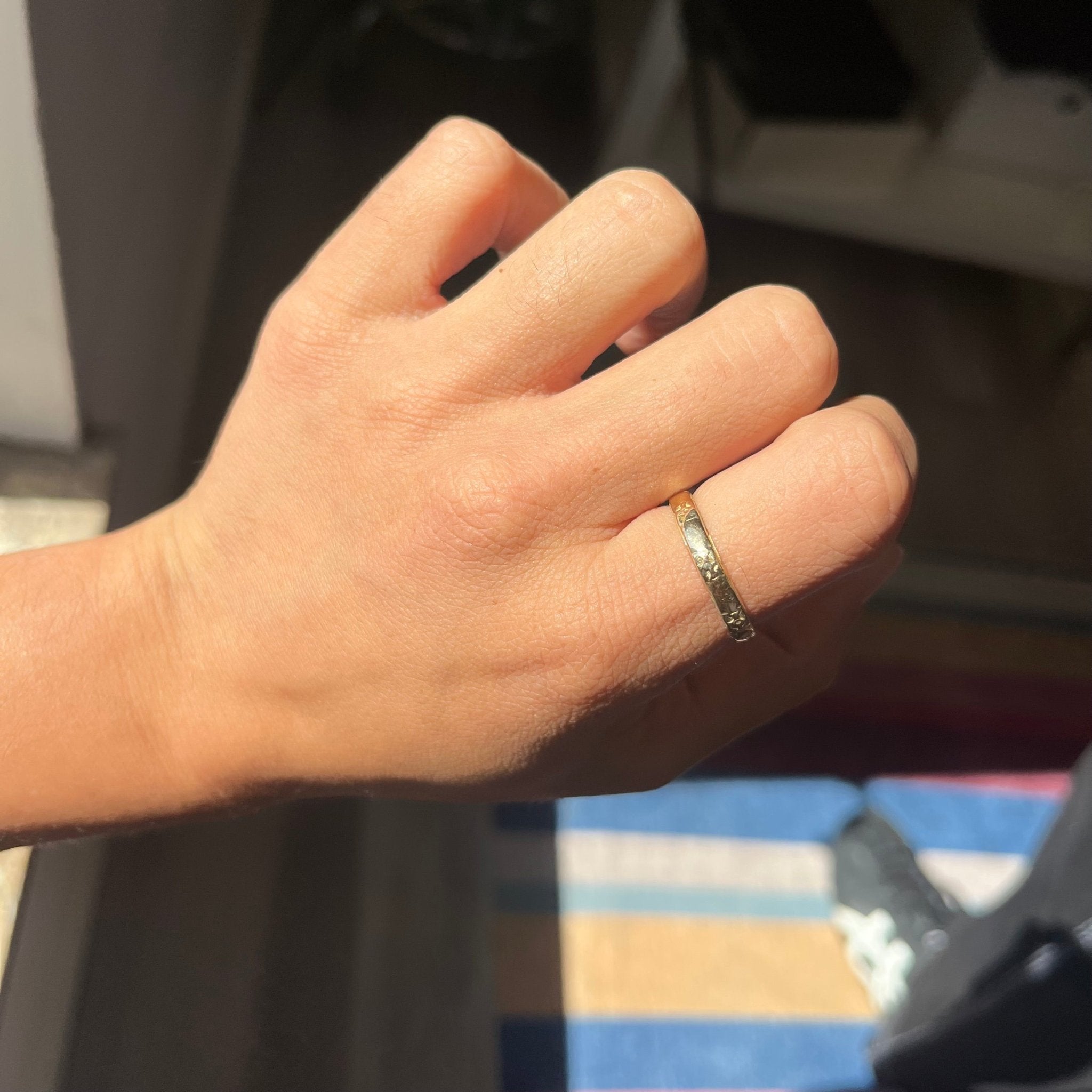 hand shot of warm antique yellow gold band with floral etched finish