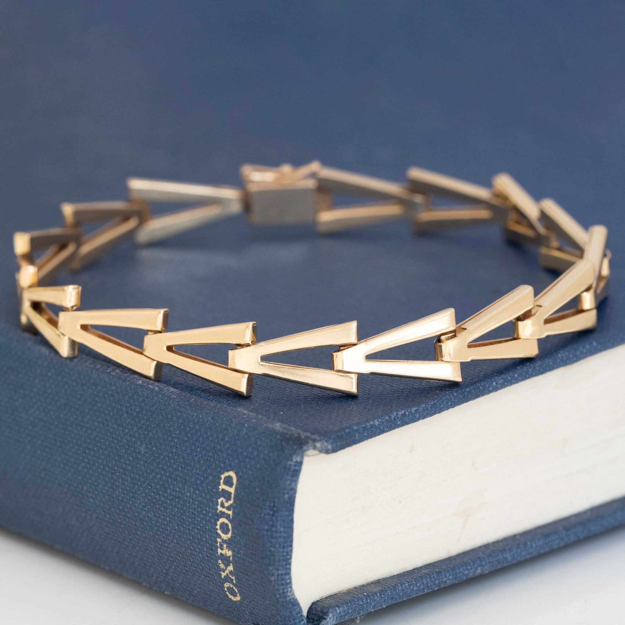 Close-up of modern gold bracelet featuring interlocking V-shaped links.