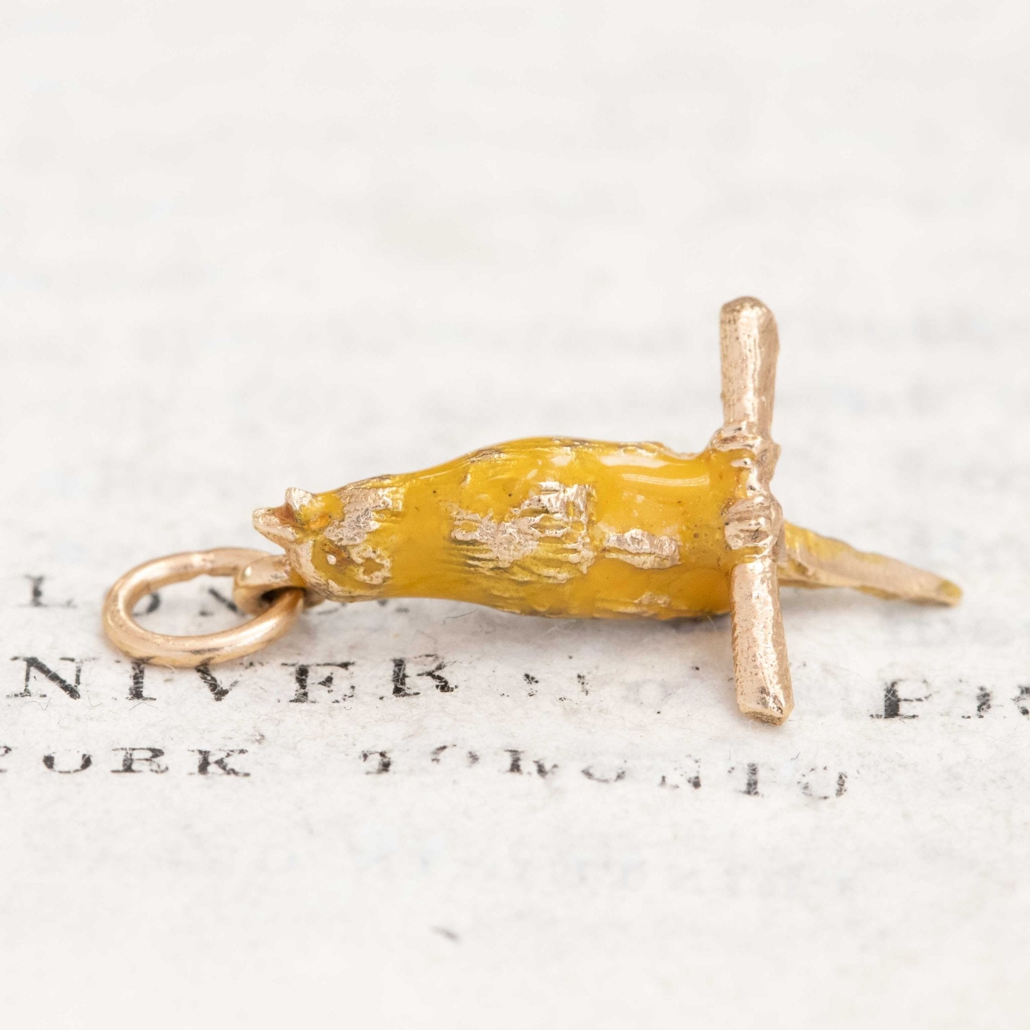 Close-up of figural canary pendant in yellow enamel over gold.