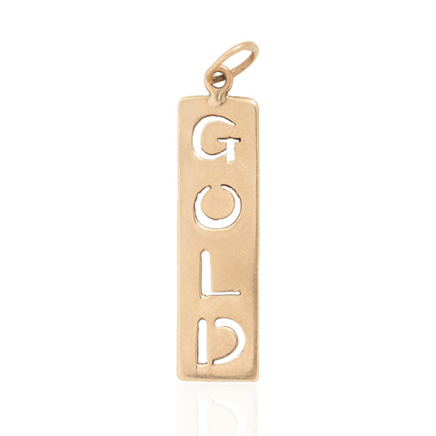 A vertical rectangular vintage gold pendant with the word 'GOLD' cut out in large letters, featuring a small top loop, shown on a white background with a faint reflection below.