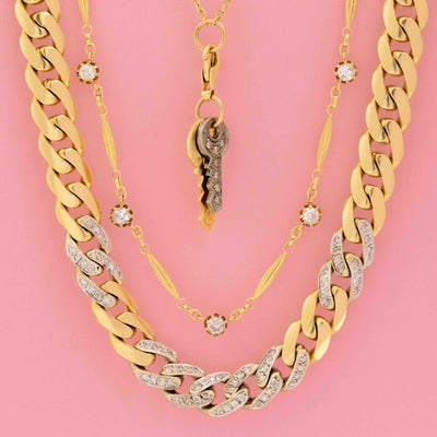 Layered vintage gold necklaces featuring diamond pavé curb chains, antique key pendant, and diamond station necklace