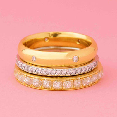 Stack of vintage gold and diamond wedding bands including an old mine cut eternity band, pavé diamond band, and bezel-set dot band