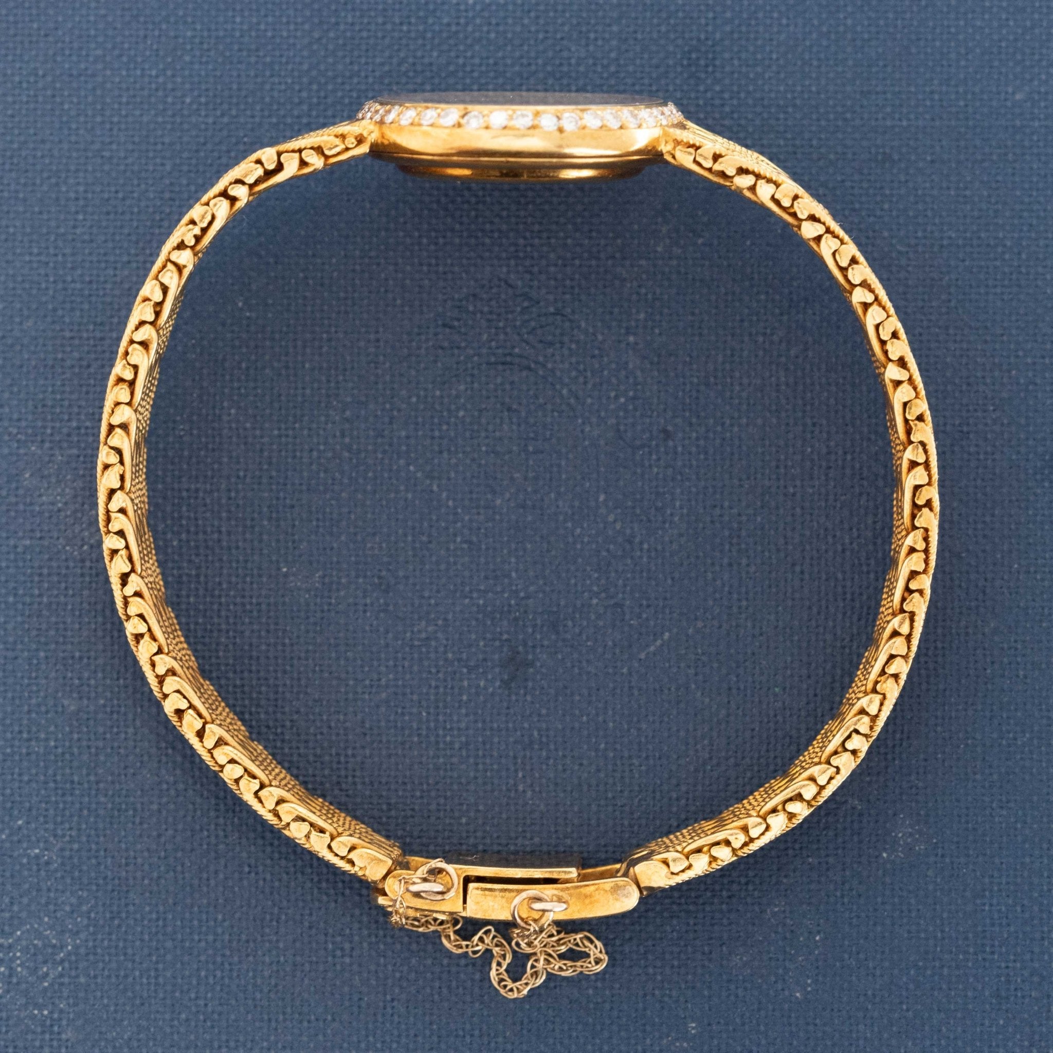 Gold bracelet with intricate design on a blue background