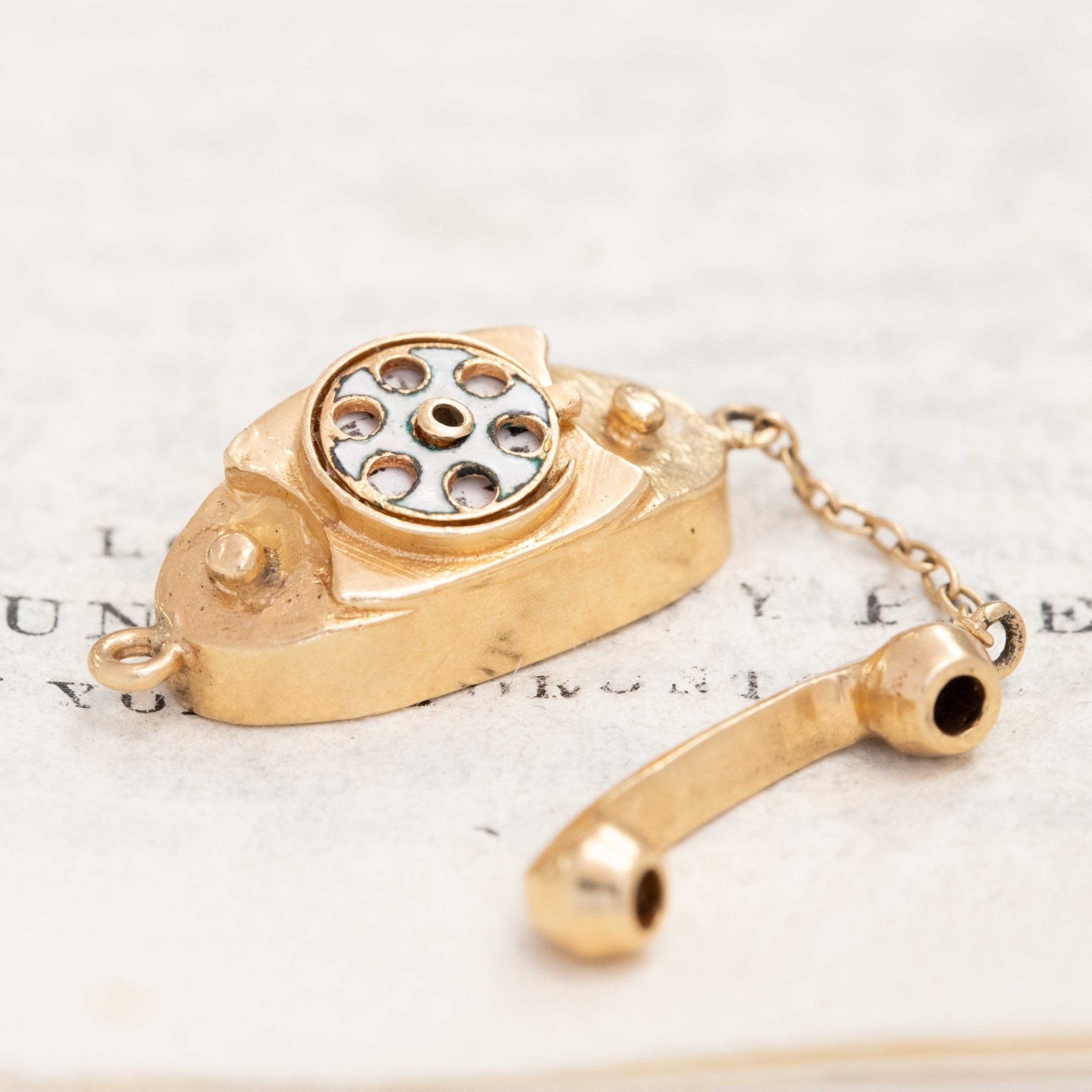 Quirky gold charm shaped like a rotary phone spelling ‘I Love You