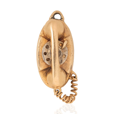 A vintage-style gold wall telephone ornament or charm with a coiled cord, photographed against a clean white background.