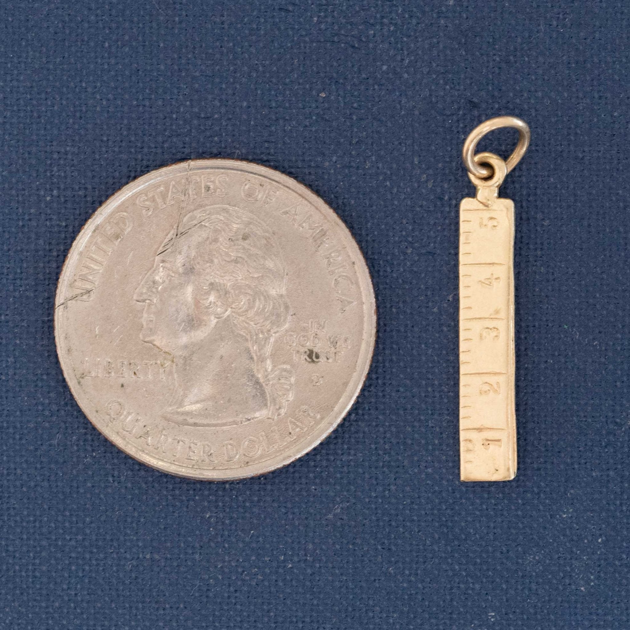 miniature ruler charm shown next to a quater