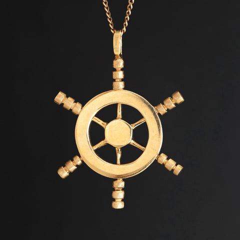 Vintage 14k yellow gold ship’s wheel pendant, nautical-inspired jewelry charm.