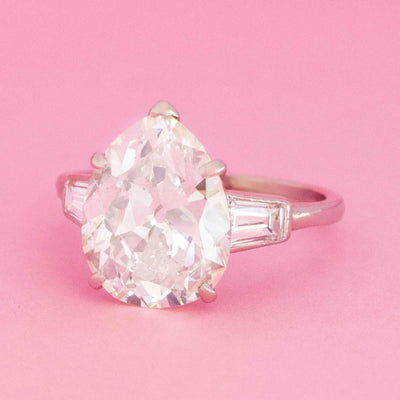 Vintage Van Cleef & Arpels pear cut diamond ring in platinum with old cut chunky stone on pink background