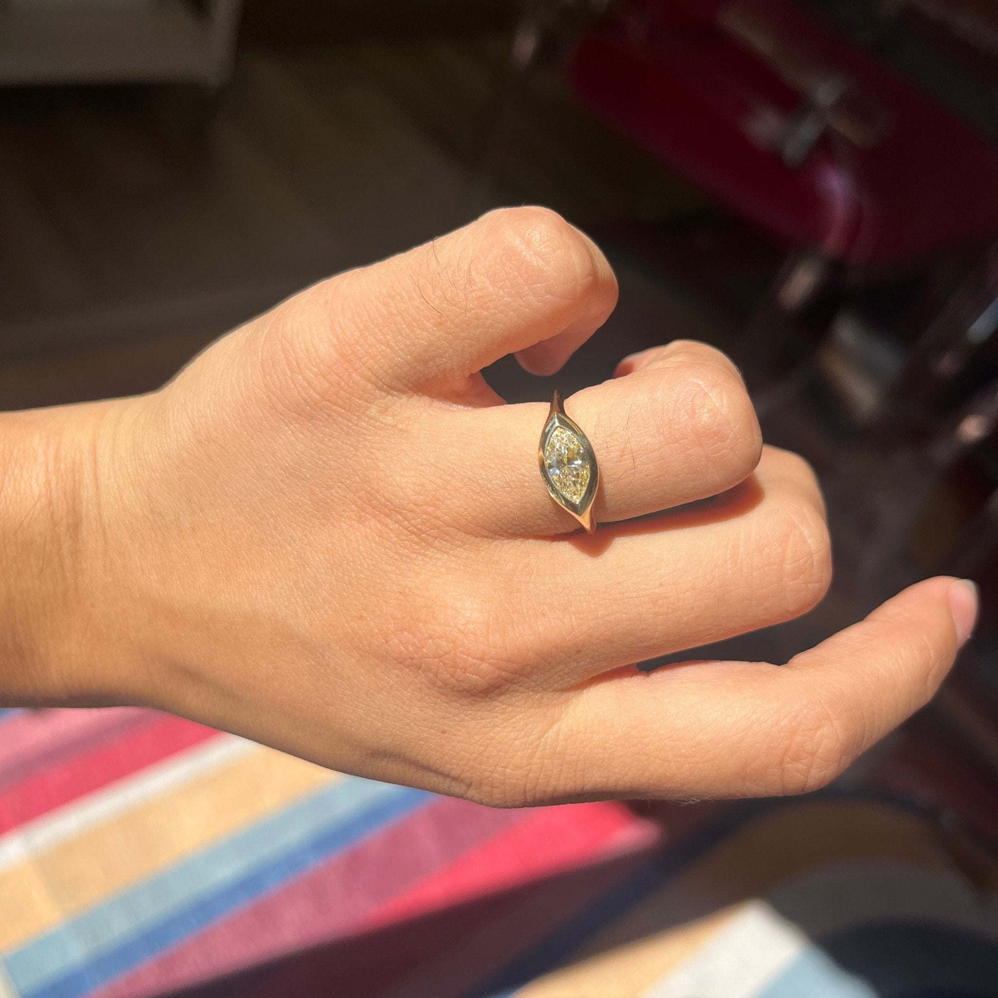 Close-up of GIA certified marquise diamond bezel setting and a knife edge shank, shown on a hand