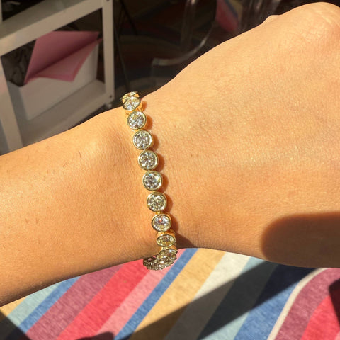 Model wearing 11.44ctw Old European Cut Diamond Bezel Tennis Bracelet in yellow gold for effortless elegance.