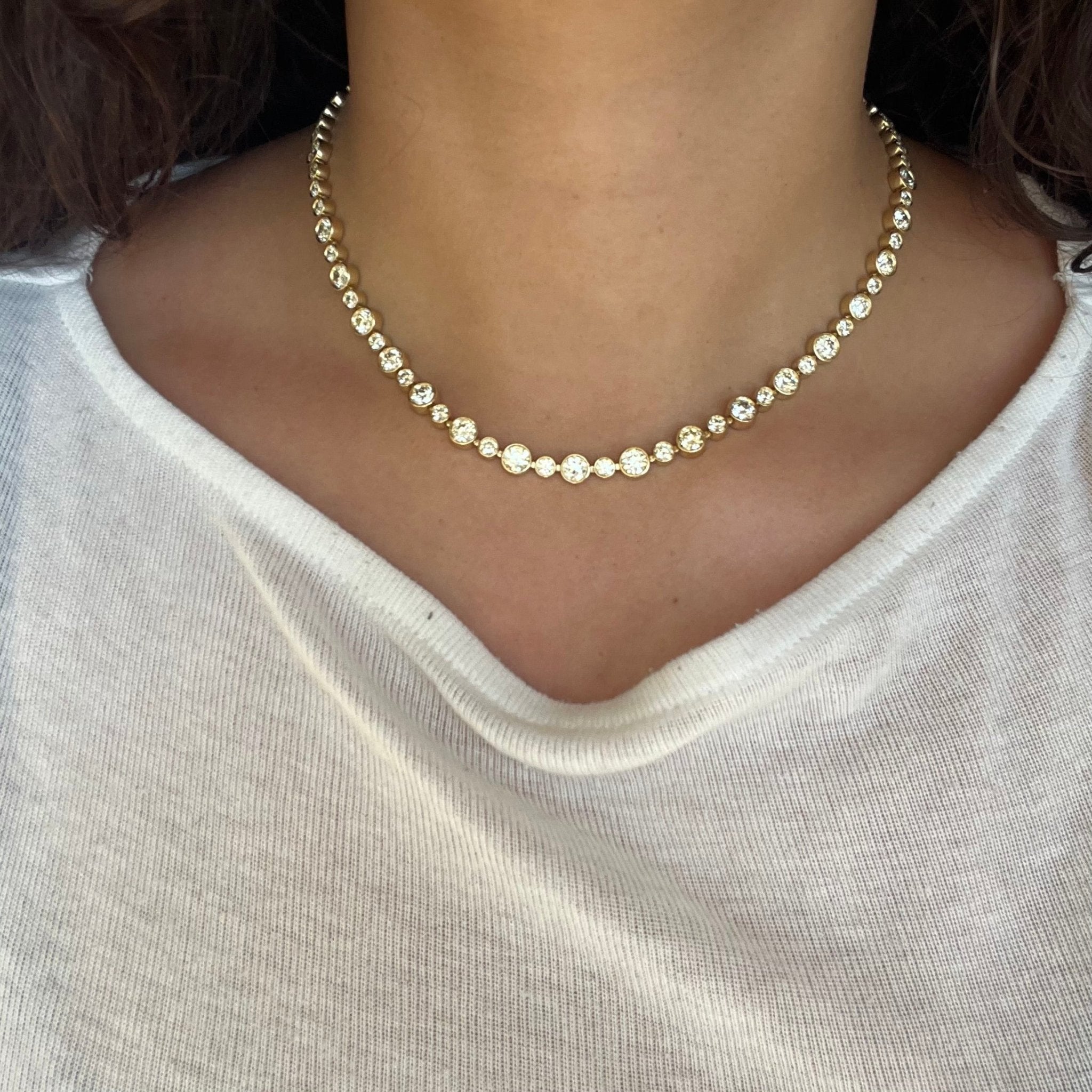 Close-up of vintage-style OEC diamond necklace, alternating bezel-set stones in yellow gold.