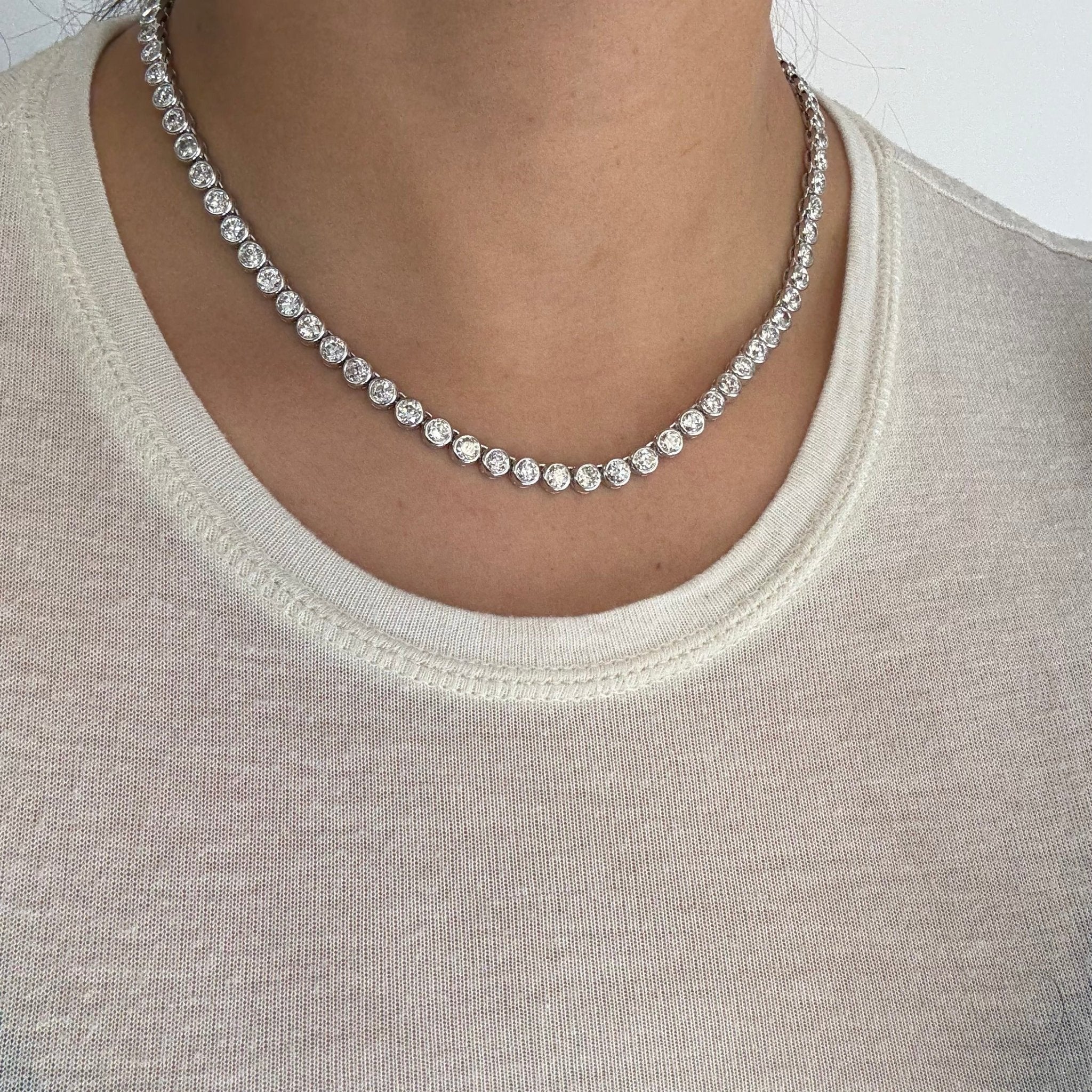 Full view of platinum diamond tennis necklace displayed on model. Old European cut diamond rivière necklace sparkling in sunlight