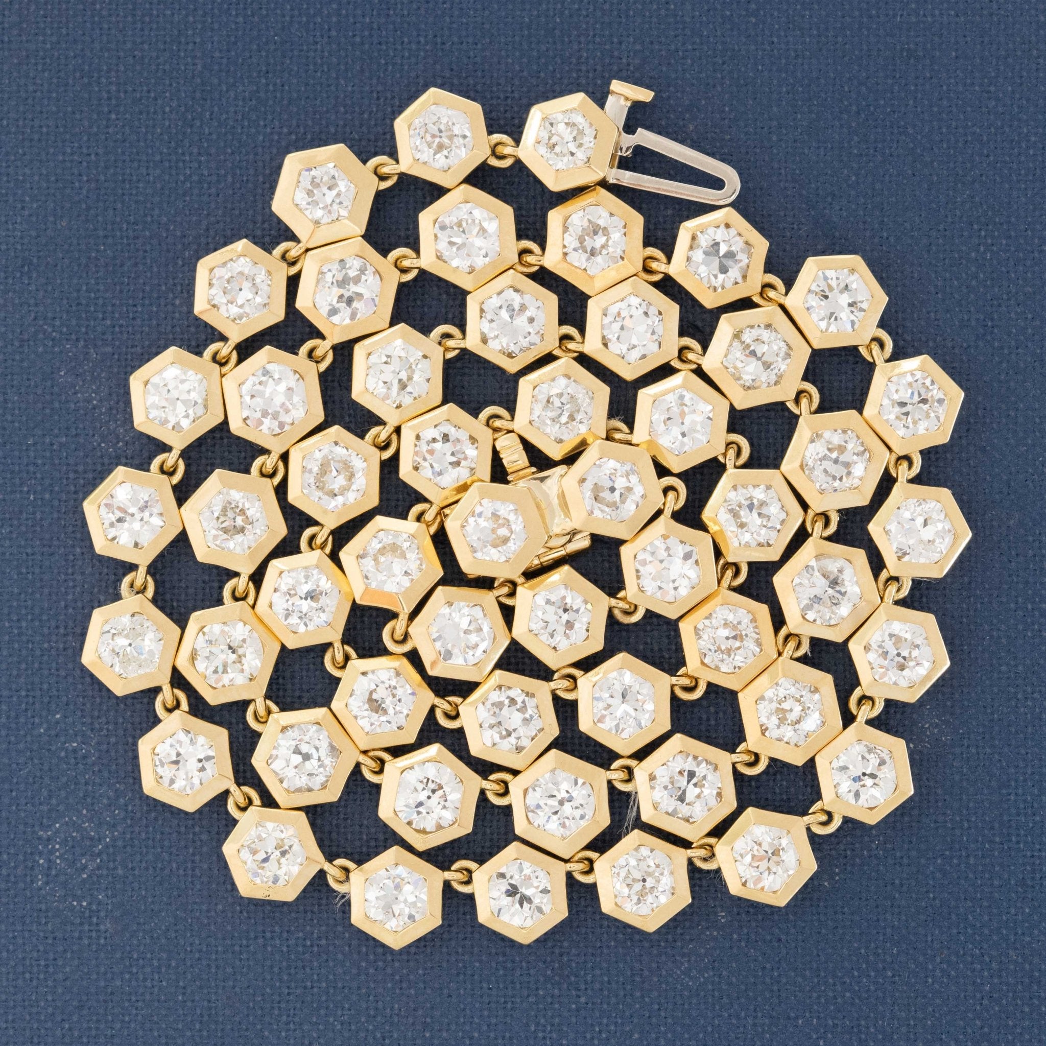 Close-up of hexagonal bezel-set Old European cut diamonds in graduated design. Detailed shot highlighting hexagonal bezel craftsmanship in yellow gold