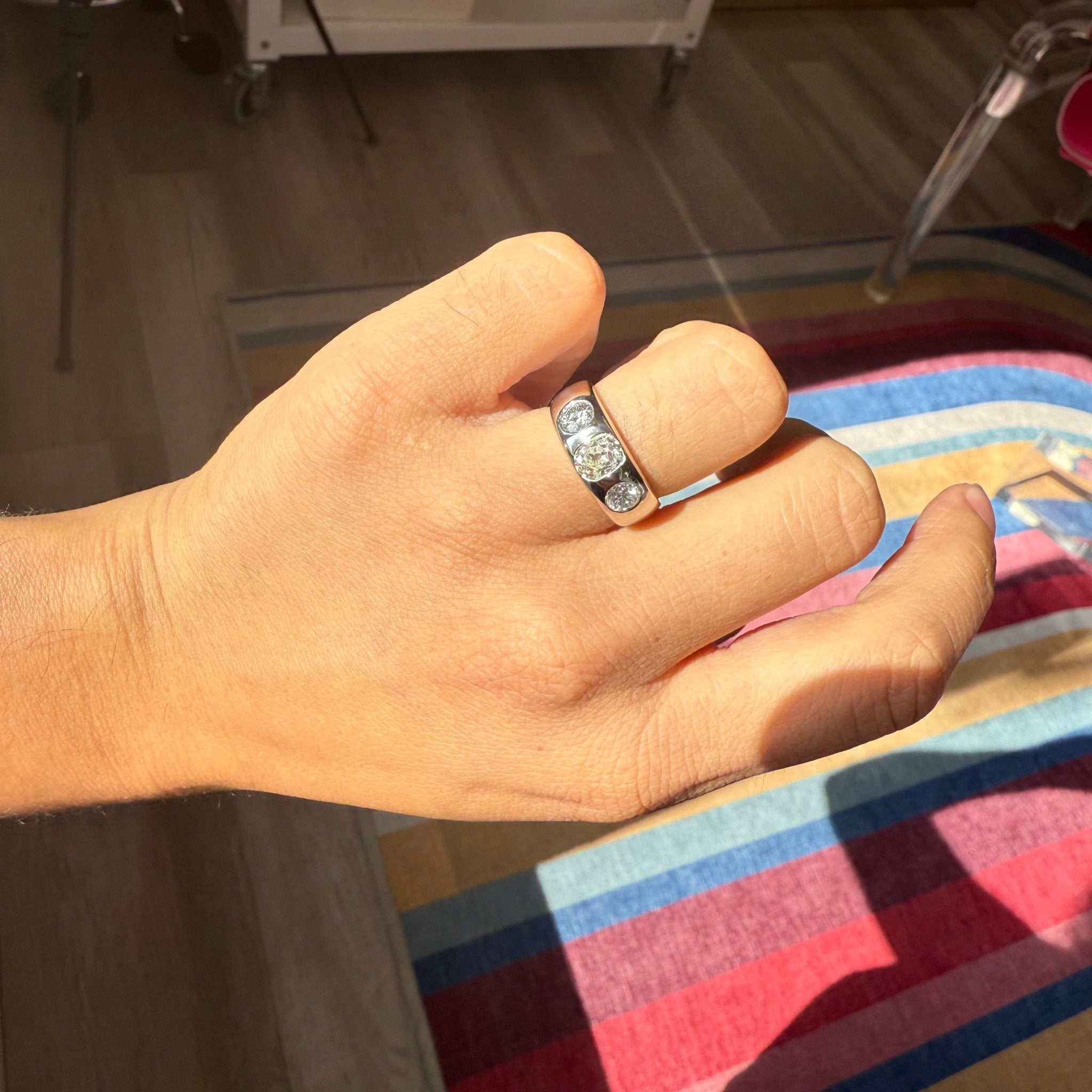 Three-stone diamond ring, Old Mine &amp; Old European cuts shown on a hand