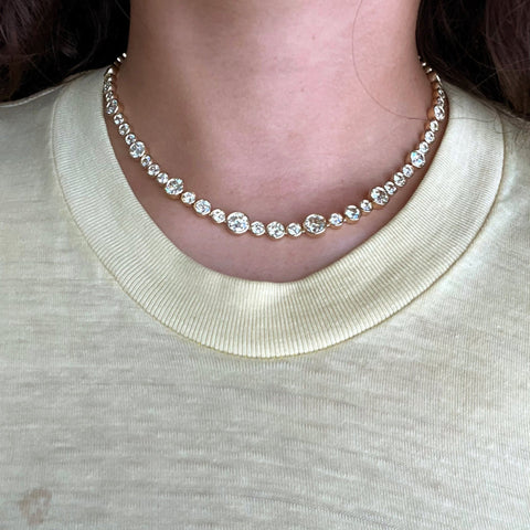 Riviere with bezel set old European cut diamonds in varying sizes in yellow gold.  The differing sizes give the piece a more contemporary feel yet so unique in that the diamonds are all vintage diamonds.  Shown here being worn by a model.