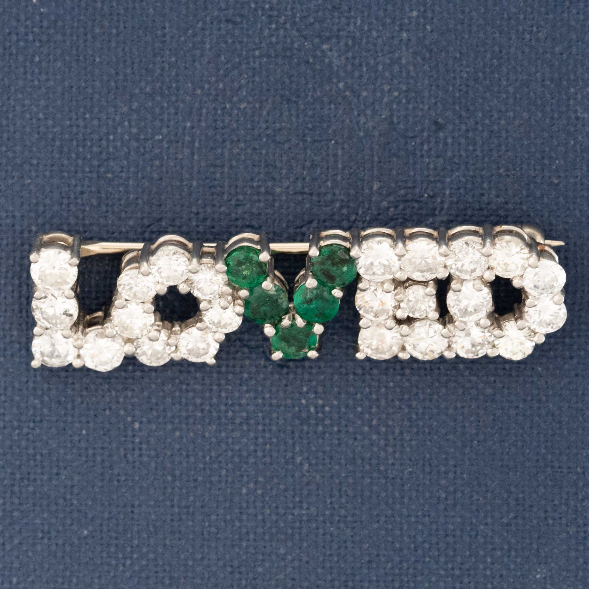 Vintage “LOVED” brooch with diamonds and emeralds on navy background