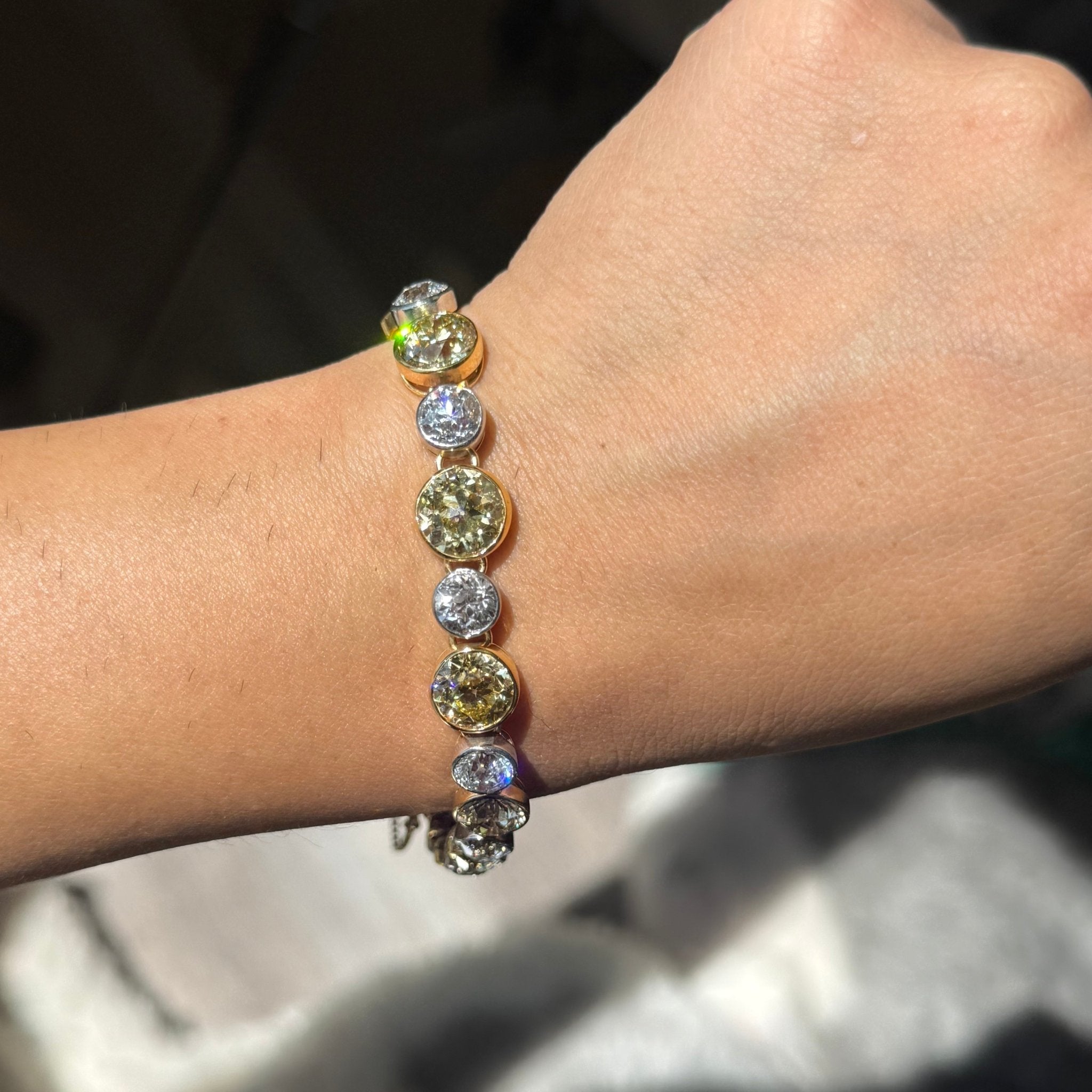 Antique line bracelet featuring 12 fancy yellow and 12 near-colorless old European cut diamonds bezel set in 18K gold and platinum, 28ctw