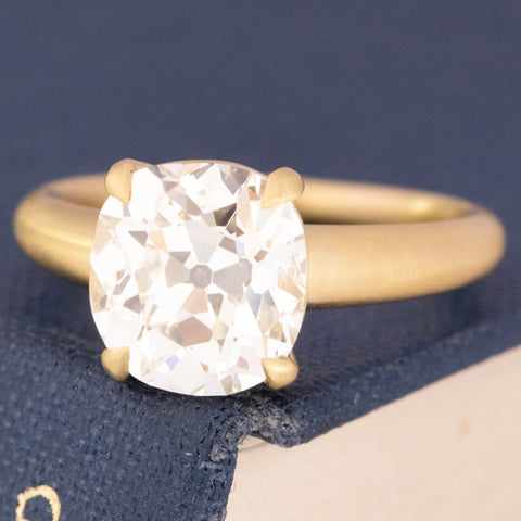 Broad-faceted Old Mine Cut diamond in yellow gold satin finish setting.