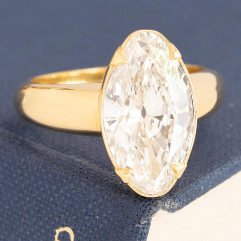 Unique moval diamond ring with thin gold frame and fold-over prongs.