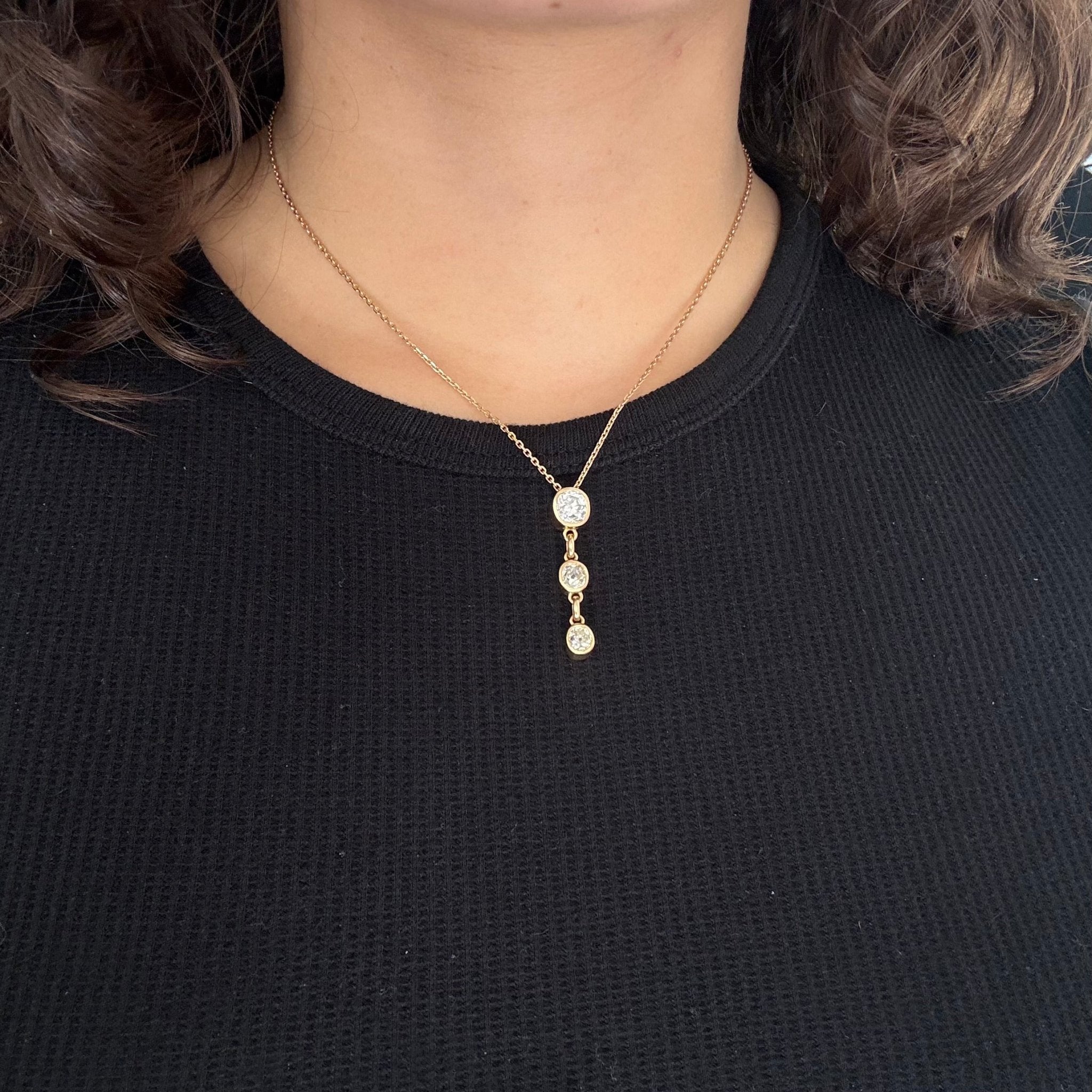 Gold necklace with three round pendants on a black shirt
